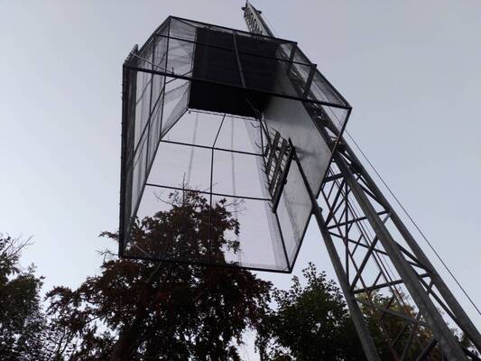 A metal cage with no bottom raised on a crane-like structure.